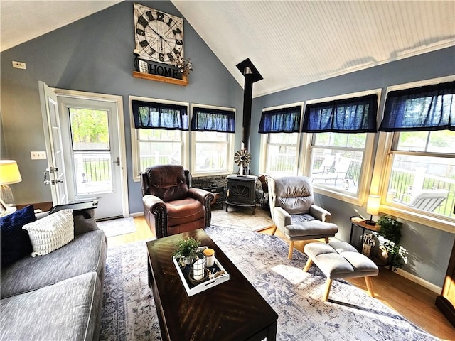 living room with high vaulted ceiling, a healthy amount of sunlight, a wood stove, and wood finished floors