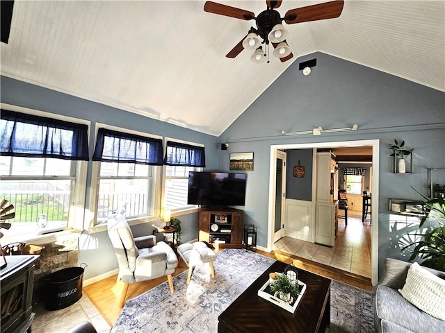 living area featuring baseboards, ceiling fan, wood finished floors, and vaulted ceiling