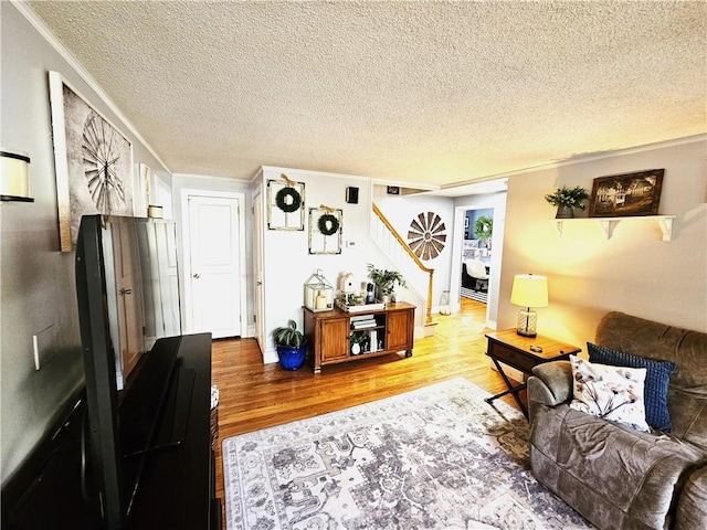 living area featuring crown molding, a textured ceiling, wood finished floors, and stairway