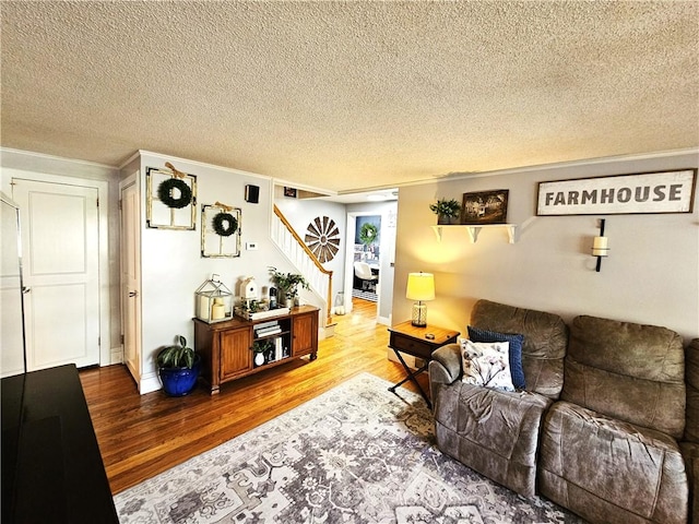 living area featuring crown molding, a textured ceiling, stairs, and wood finished floors