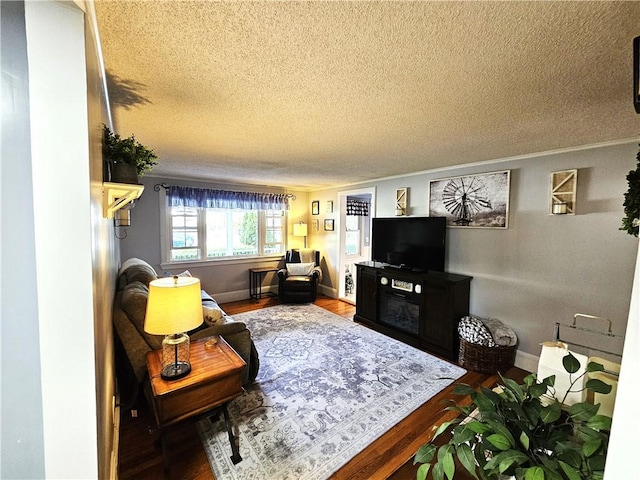 living room with crown molding, baseboards, a textured ceiling, and wood finished floors