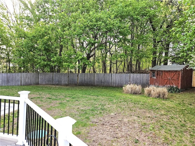 view of yard with a fenced backyard, a shed, and an outbuilding