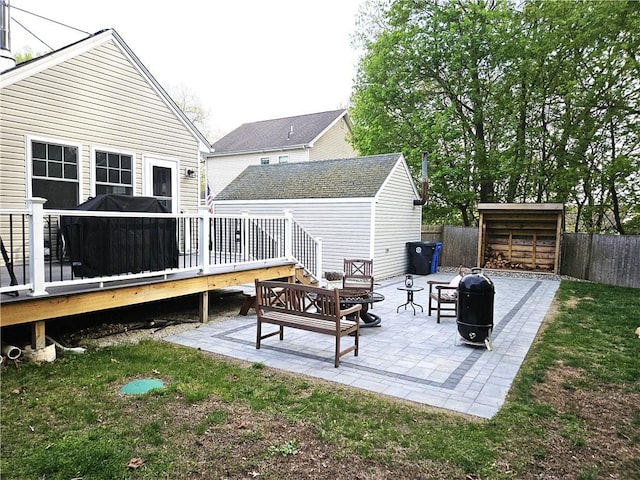 rear view of property with a deck, a fenced backyard, an outbuilding, a patio area, and a storage shed