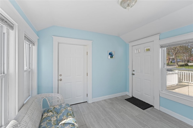foyer with baseboards, light wood-style floors, and lofted ceiling