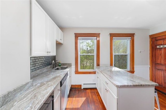 kitchen featuring a baseboard radiator, a sink, a peninsula, dark wood-type flooring, and stainless steel dishwasher