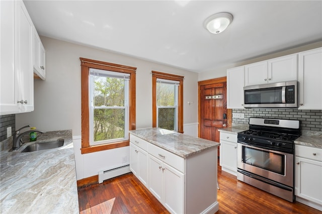 kitchen featuring light stone countertops, a baseboard heating unit, a sink, dark wood finished floors, and appliances with stainless steel finishes
