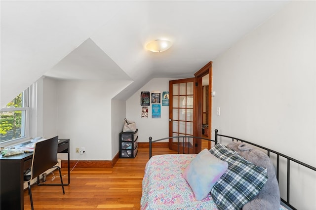 bedroom with baseboards, wood finished floors, and vaulted ceiling