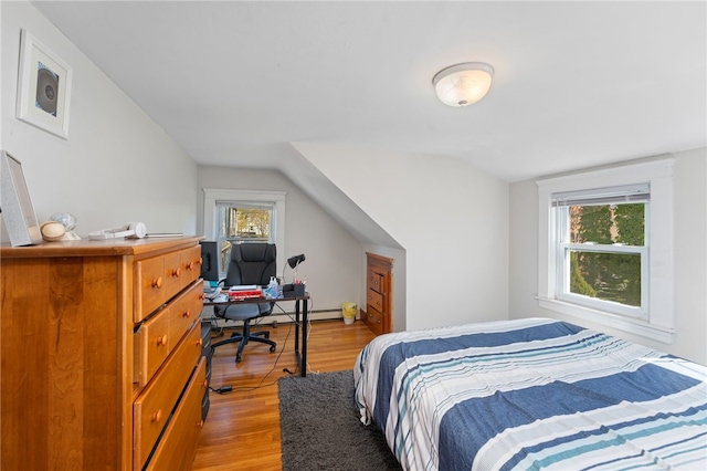 bedroom with a baseboard heating unit, light wood-type flooring, and lofted ceiling