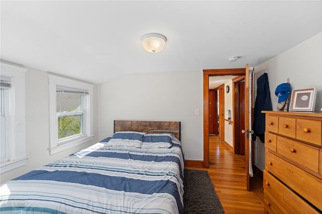 bedroom with baseboards, wood finished floors, and vaulted ceiling