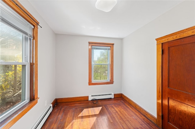 empty room featuring baseboards, a baseboard heating unit, and hardwood / wood-style floors