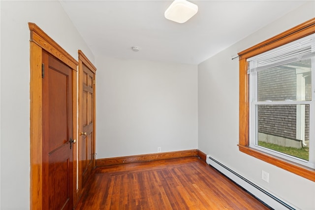 unfurnished room featuring baseboards, baseboard heating, and hardwood / wood-style flooring