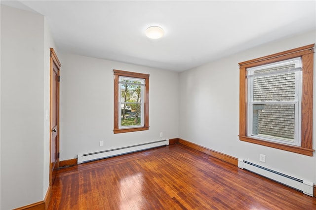spare room with wood-type flooring, baseboards, and a baseboard heating unit
