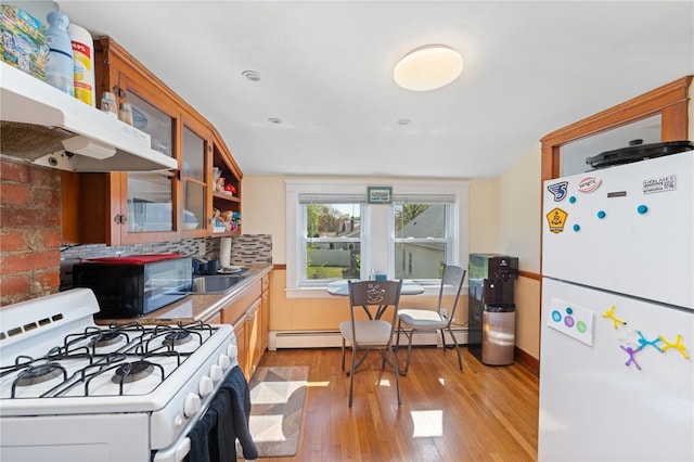 kitchen with baseboard heating, light wood-type flooring, glass insert cabinets, under cabinet range hood, and white appliances