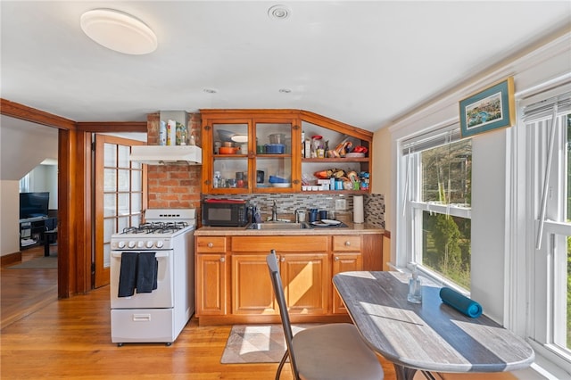 kitchen featuring black microwave, tasteful backsplash, a sink, white range with gas stovetop, and light wood-type flooring