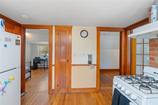 kitchen with baseboards, light wood-type flooring, and white appliances