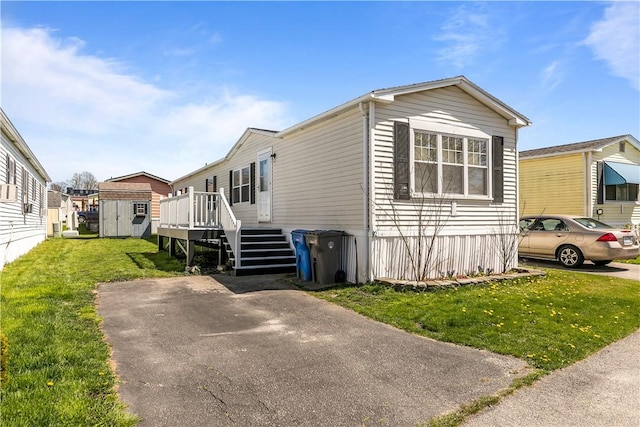 manufactured / mobile home featuring a front yard, a deck, an outbuilding, a storage unit, and stairs