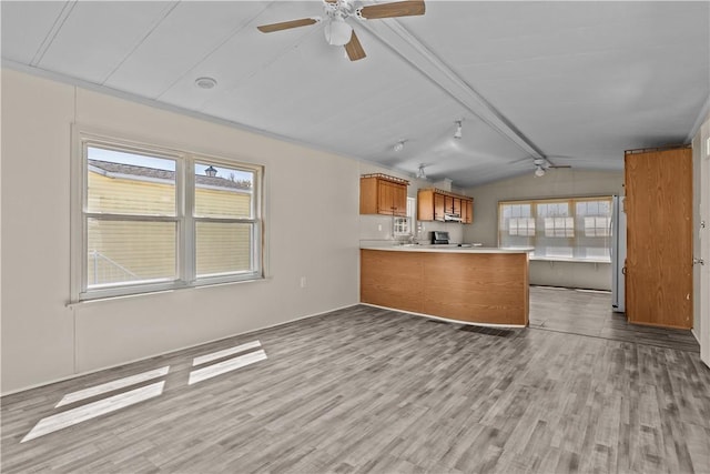interior space with brown cabinetry, light countertops, lofted ceiling with beams, a peninsula, and light wood-style flooring