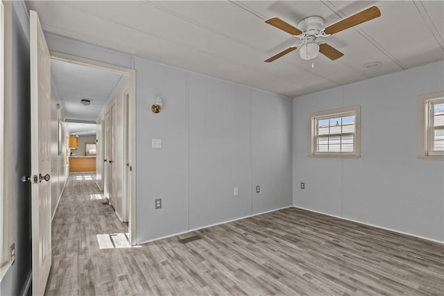 empty room with a ceiling fan and light wood-style flooring