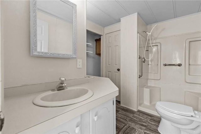 bathroom featuring wood finished floors, a stall shower, toilet, and vanity