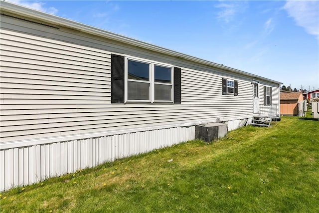 view of side of home featuring entry steps, a yard, and cooling unit