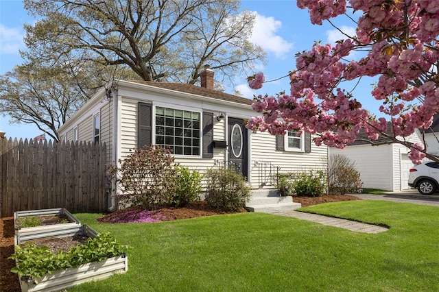 view of front of property with fence, a chimney, a vegetable garden, and a front yard