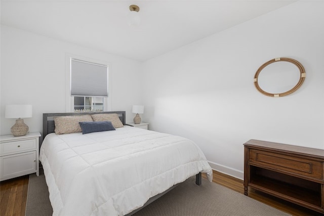 bedroom with baseboards and dark wood-style flooring