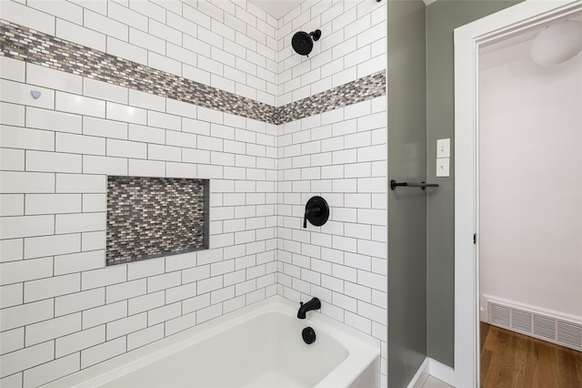 bathroom with baseboards, shower / bath combination, visible vents, and wood finished floors