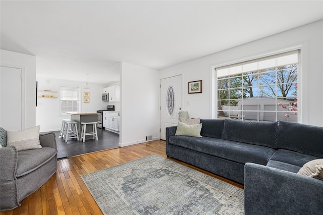 living room with dark wood-style flooring and visible vents