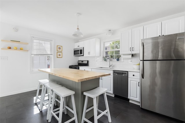 kitchen featuring butcher block countertops, a breakfast bar area, white cabinetry, a sink, and appliances with stainless steel finishes