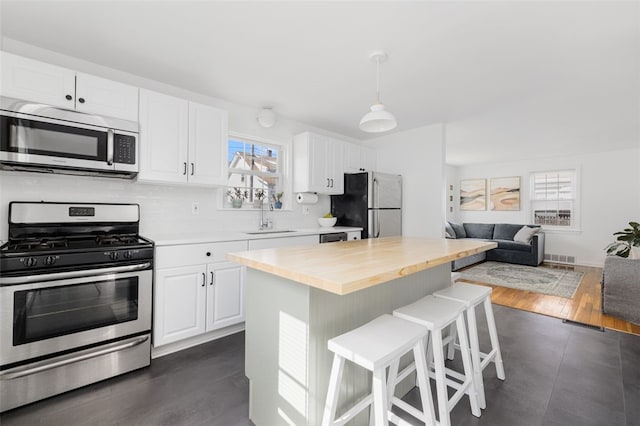 kitchen featuring a sink, appliances with stainless steel finishes, white cabinets, and a kitchen bar