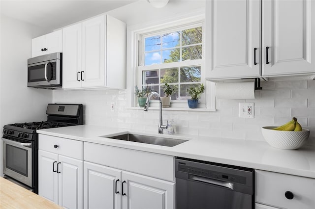 kitchen with light countertops, a sink, backsplash, and stainless steel appliances
