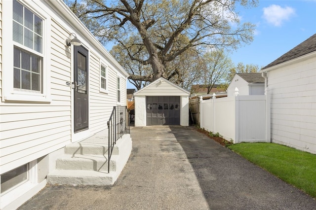 view of side of home with a garage, fence, and an outbuilding