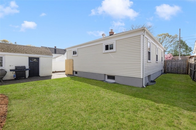 back of property with a lawn, an outbuilding, and a fenced backyard