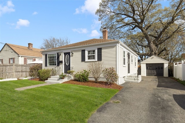 view of front of property featuring a chimney, an outbuilding, a detached garage, fence, and a front lawn