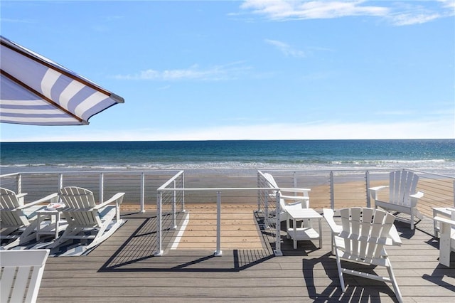 wooden terrace featuring a beach view and a water view