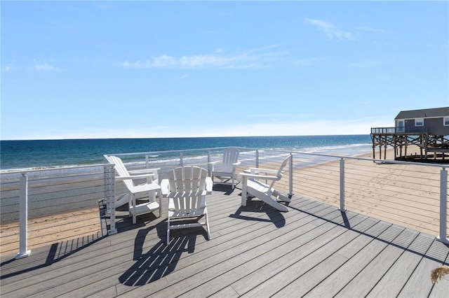 wooden deck featuring a water view and a beach view