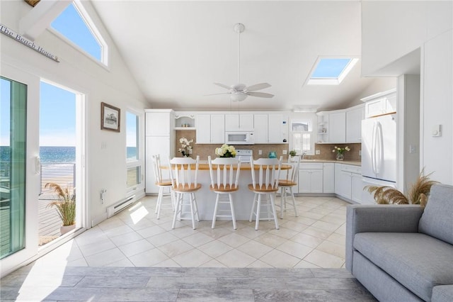 kitchen featuring open shelves, white appliances, open floor plan, tasteful backsplash, and a baseboard heating unit