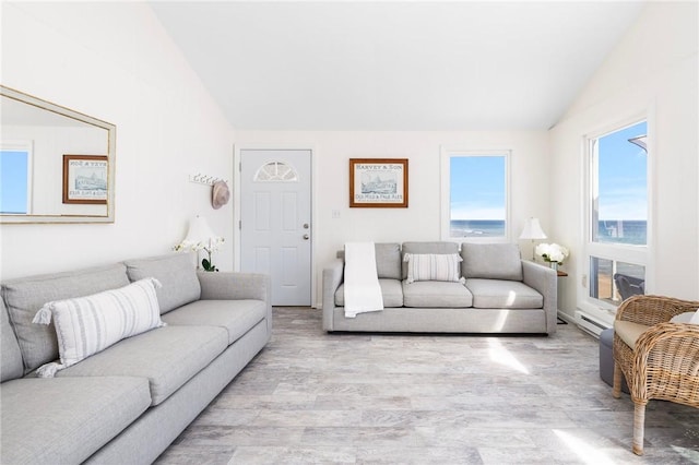 living room featuring vaulted ceiling, a baseboard radiator, and light wood-style floors