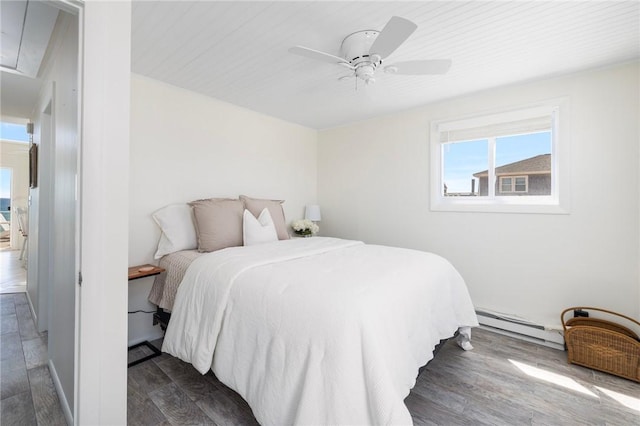 bedroom with ceiling fan, baseboard heating, and dark wood-type flooring