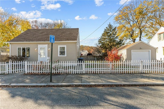 view of front facade featuring a fenced front yard, an outbuilding, and a detached garage