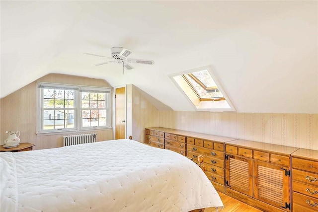 bedroom with radiator, lofted ceiling with skylight, ceiling fan, wallpapered walls, and light wood-style flooring