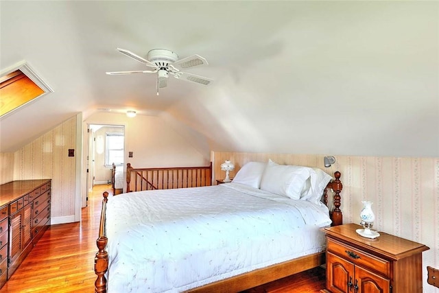 bedroom featuring wallpapered walls, visible vents, wood finished floors, and lofted ceiling