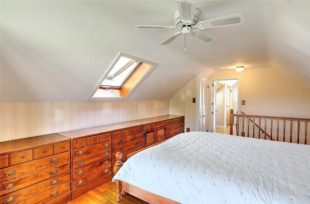 bedroom featuring vaulted ceiling with skylight, a ceiling fan, and light wood-style flooring