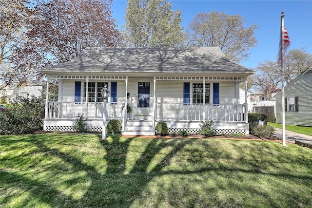 view of front of house with covered porch, a shingled roof, and a front yard