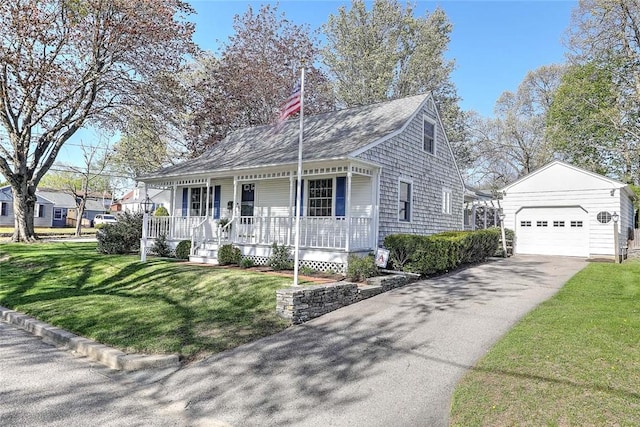 view of front of property featuring a front yard, a shingled roof, an outbuilding, a porch, and driveway