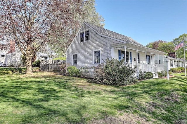 view of property exterior with covered porch, a yard, and fence