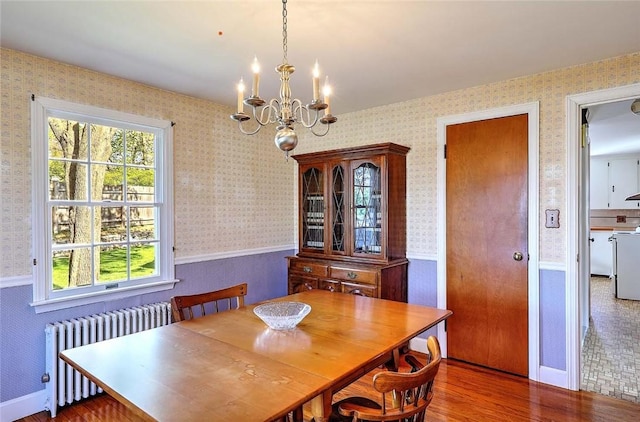 dining space with wood finished floors, a wainscoted wall, a chandelier, radiator heating unit, and wallpapered walls