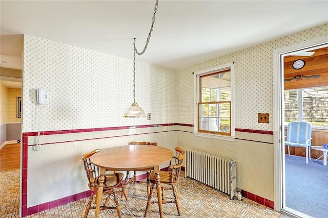 dining room with radiator heating unit, wainscoting, and wallpapered walls