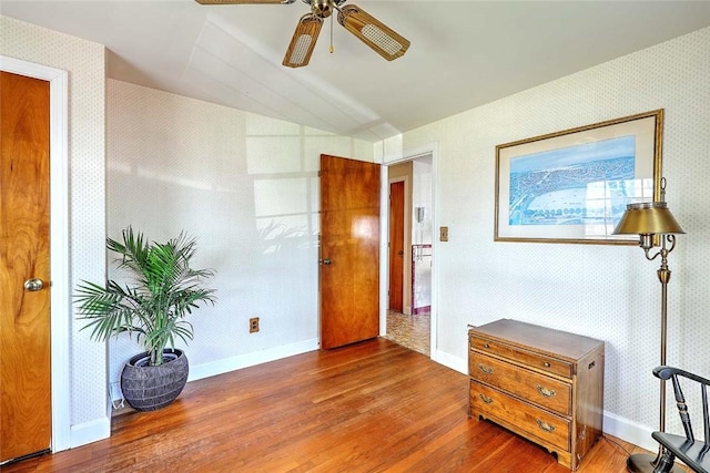 foyer entrance featuring baseboards, wood finished floors, and wallpapered walls