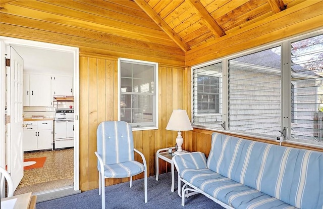 sunroom / solarium with wooden walls, lofted ceiling with beams, wooden ceiling, and carpet